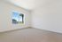 Pet-Friendly Luxury Apartments in Nampa, ID - The Station Apartments at Gateway - An Empty Bedroom With White Walls, Beige Carpet, And Large Window Showing Blue Sky.