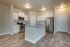 Dog-Friendly Apartments in Boise, ID - Kensington - An Open Kitchen with Two-Tone Paint, 9-Foot Ceiling, Wood-Style Flooring, Single Sink Kitchen Island, Huge Corner Pantry, Customized Cabinetry with Crown Molding, Granite Countertops, Stainless Steel Appliances Including Oven, Refrigerator, and Built-In Microwave, and Light Fixtures.