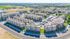 Aerial view of a modern apartment complex with multiple buildings, ample parking, and lush greenery, set in a vibrant suburban neighborhood.