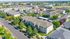 Aerial view of a picturesque apartment community surrounded by lush greenery, showcasing modern architecture and ample parking, perfect for urban living.