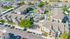 Aerial view of a vibrant apartment community featuring modern buildings, lush green spaces, and a luxurious central pool area, perfect for comfortable living.