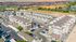 Aerial view of a vibrant apartment community featuring modern buildings, lush green spaces, and a luxurious central pool area, perfect for comfortable living.
