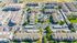 Aerial view of a vibrant apartment complex with modern buildings, lush green spaces, and a central swimming pool, creating a welcoming community atmosphere.