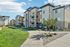 Modern apartment complex with chic stone facade and well-maintained landscaping under a bright blue sky.