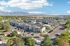 Aerial view of a modern apartment complex with beautifully landscaped surroundings and mountain views, featuring ample parking and lush greenery.