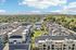 Panoramic aerial view of a modern apartment complex with a stunning pool area and lush green surroundings, set against a backdrop of picturesque mountains.