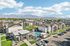 Charming apartment complex with modern buildings, a sparkling swimming pool, and scenic mountain views under a clear blue sky.