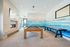 Spacious recreation room featuring a modern pool table, shuffleboard, and a vibrant beach-themed mural, perfect for entertainment and relaxation.