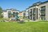 Charming apartment complex with modern design, featuring lush green lawns and a vibrant playground for families.