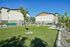 Modern apartment complex with lush green space, inviting picnic areas, and serene outdoor seating, perfect for relaxation and community enjoyment.
