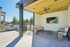 Modern outdoor lounge with cozy seating, wall-mounted TV, and sleek barbecue grill under a stylish wooden canopy.
