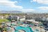 Modern apartment complex with stunning mountain views, featuring a luxurious pool area with sun loungers and umbrellas, perfect for relaxation and leisure.