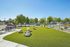Inviting outdoor community space featuring lush green lawn, picnic tables, and benches, perfect for relaxation and social gatherings.
