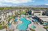 Stunning aerial view of a modern apartment complex featuring a luxurious resort-style swimming pool, surrounded by lounging areas and mountain views.