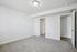 Bright and spacious room with plush carpeting, white walls, and modern lighting, perfect for a cozy bedroom or stylish home office.