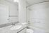 Bright, modern bathroom with elegant granite countertop, sleek fixtures, and a pristine bathtub, offering comfort and style.
