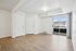 Bright living area with modern wood flooring, large sliding glass doors leading to a scenic balcony view, and crisp white walls for a spacious feel.