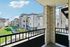 Charming apartment balcony view showcasing modern stone architecture and lush green pathways on a sunny day.