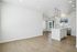 Contemporary open-plan apartment with elegant wood flooring, featuring a modern white kitchen with an island and ample natural light.