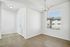Bright and inviting apartment corner featuring elegant wood flooring, modern chandelier, and a large window offering natural light with a view.