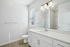 Bright and modern bathroom with a large mirror, sleek vanity, and elegant lighting, showcasing a fresh and minimalistic design.