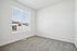 Bright and inviting empty room with plush carpet and large window offering natural light and city views.