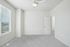 Bright and airy bedroom with plush carpet, modern ceiling fan, and large window bringing in natural light.