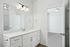 Elegant modern bathroom featuring sleek white cabinetry, a spacious mirror, and stylish lighting.
