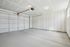 Spacious and well-lit double garage with sleek concrete flooring and modern automatic door system, perfect for ample storage and vehicle accommodation.