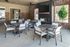 Chic outdoor seating area with modern tables and chairs, featuring a wall-mounted TV and stylish brick design.