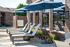 Inviting outdoor lounge area with comfortable reclined chairs and blue umbrellas beside a modern brick building.