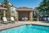 Charming outdoor pool area with comfortable loungers, elegant brick cabana, and modern grill station, perfect for relaxation and entertainment.