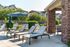 Inviting outdoor space with modern sun loungers, a large umbrella, and lush greenery&mdash;perfect for relaxation in a vibrant apartment community.