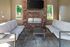 Inviting outdoor seating area with cozy sofas, a stylish brick fireplace, and modern decor. Ideal for relaxation and entertainment.