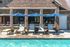 Inviting poolside oasis with sleek lounge chairs and blue umbrellas against a charming brick facade.