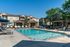Luxurious apartment complex with a sparkling outdoor pool, sun loungers, shaded cabanas, and lush greenery, perfect for relaxation and enjoyment.