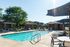 Inviting outdoor pool area with sun loungers and shaded seating, perfect for relaxation and leisure in a serene residential community.