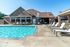 Inviting outdoor pool area with modern lounge chairs and shaded tables, perfect for relaxation and social gatherings.