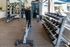 Bright and modern gym equipped with a variety of weights, benches, and exercise machines, complemented by large windows for natural light.