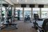 Modern gym with advanced fitness equipment, sunny windows, and poolside views for an invigorating workout experience.