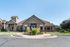 Charming clubhouse exterior with stone facade, landscaped entrance, and a striking sculpture centerpiece.