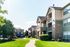 Sunny apartment complex with charming balconies, lush greenery, and playground access.