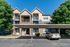 Charming apartment complex with brick and siding facade, nestled between lush green trees. Features covered parking and inviting balconies.