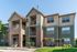 Charming three-story apartment building with inviting balconies, modern brick accents, and lush landscaping on a sunny day.