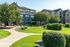 Charming apartment complex with lush landscaping, featuring well-maintained lawns, vibrant shrubs, and mature trees under a clear blue sky.