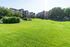 Vibrant apartment community with lush green lawns and modern buildings nestled among mature trees, perfect for relaxed living.