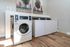Modern and inviting laundry room featuring state-of-the-art washing machines and stylish wood flooring.