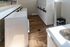 Bright and modern laundry room featuring multiple washers and dryers with sleek white design, complemented by elegant wood flooring and ample counter space.
