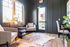 Chic and cozy apartment lounge featuring modern armchairs, stylish lighting, and a natural fiber rug. Bright window and subtle decor create an inviting atmosphere.
