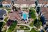 Aerial view of a luxurious apartment complex featuring a sparkling central swimming pool, beautifully landscaped paths, and vibrant green spaces.